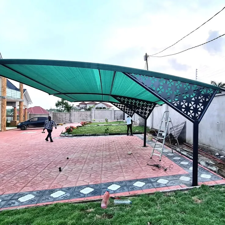 Green shade-net car port with laser-cut decorative steel frame panels spanning two bays